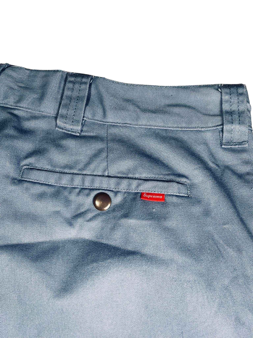 Világoskék streetwear nadrág, hátsó zseb piros Supreme címkével, fém patenttal