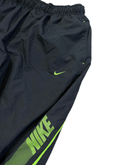 Fekete Nike streetwear melegítőnadrág zöld logóval, vintage stílusban