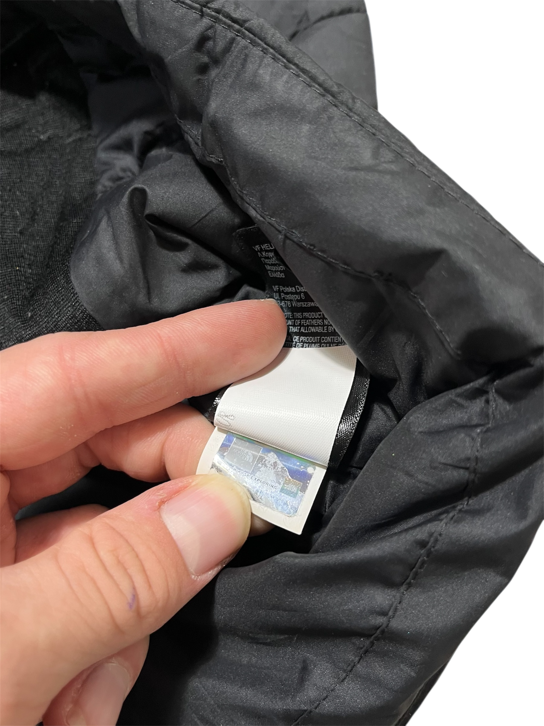 Fekete streetwear kabát belső címke, hologramos hitelesítő matrica közelről